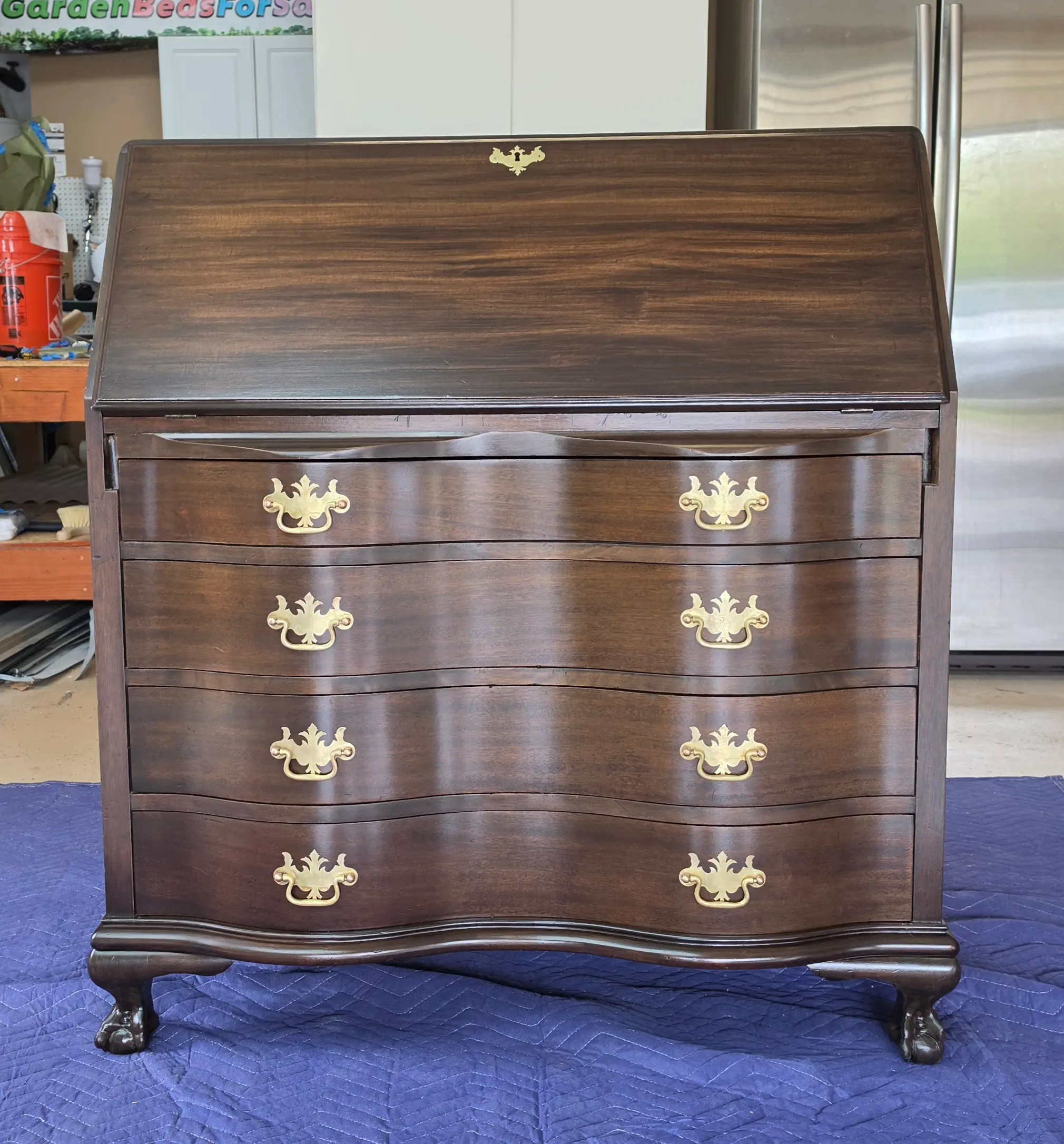 The same antique secretary desk after restoration, refinished with cleaned brass hardware and ball and claw feet