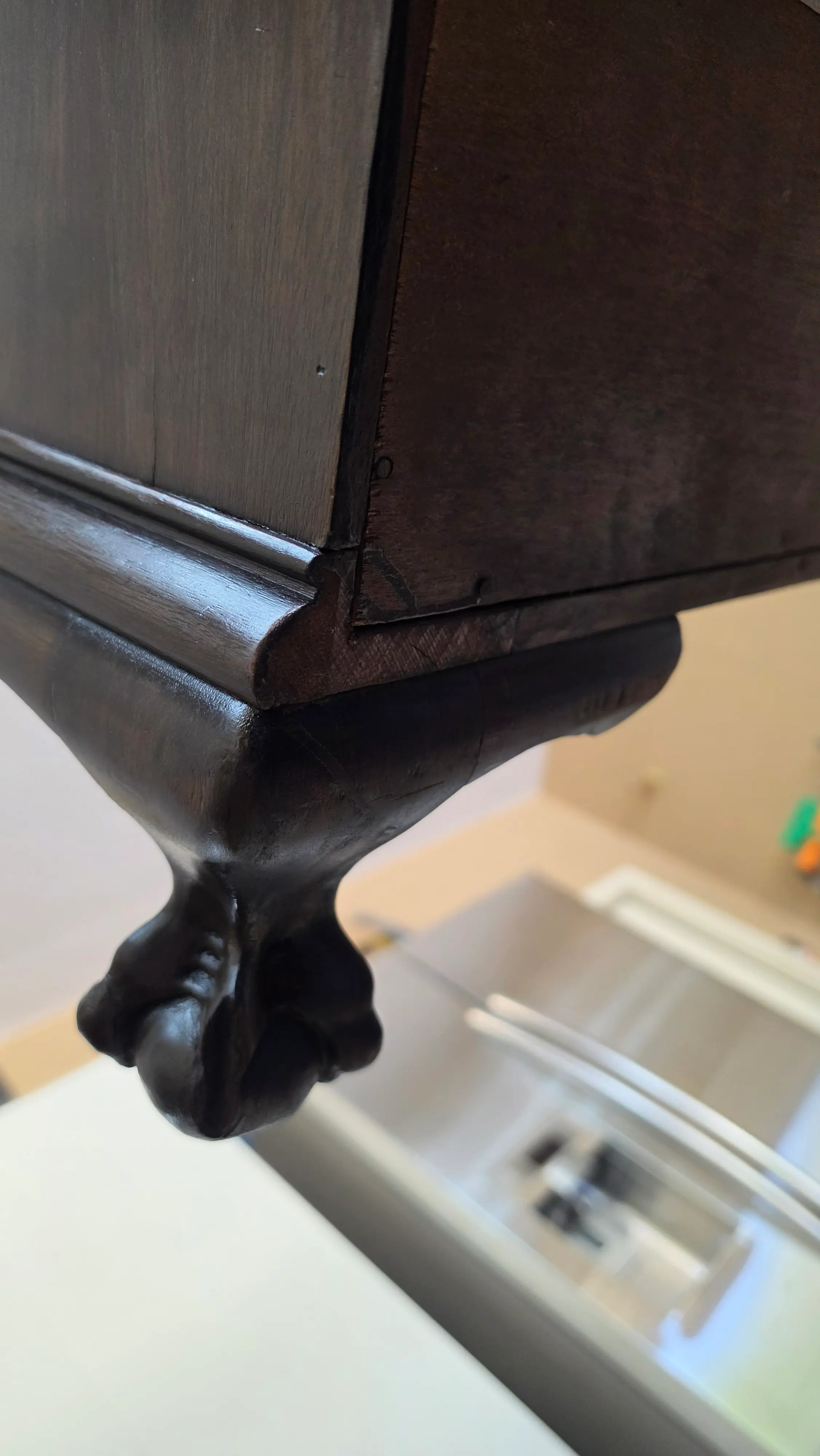 The same carved ball and claw foot after restoration, the carving sharp again and the finish rebuilt to match the case