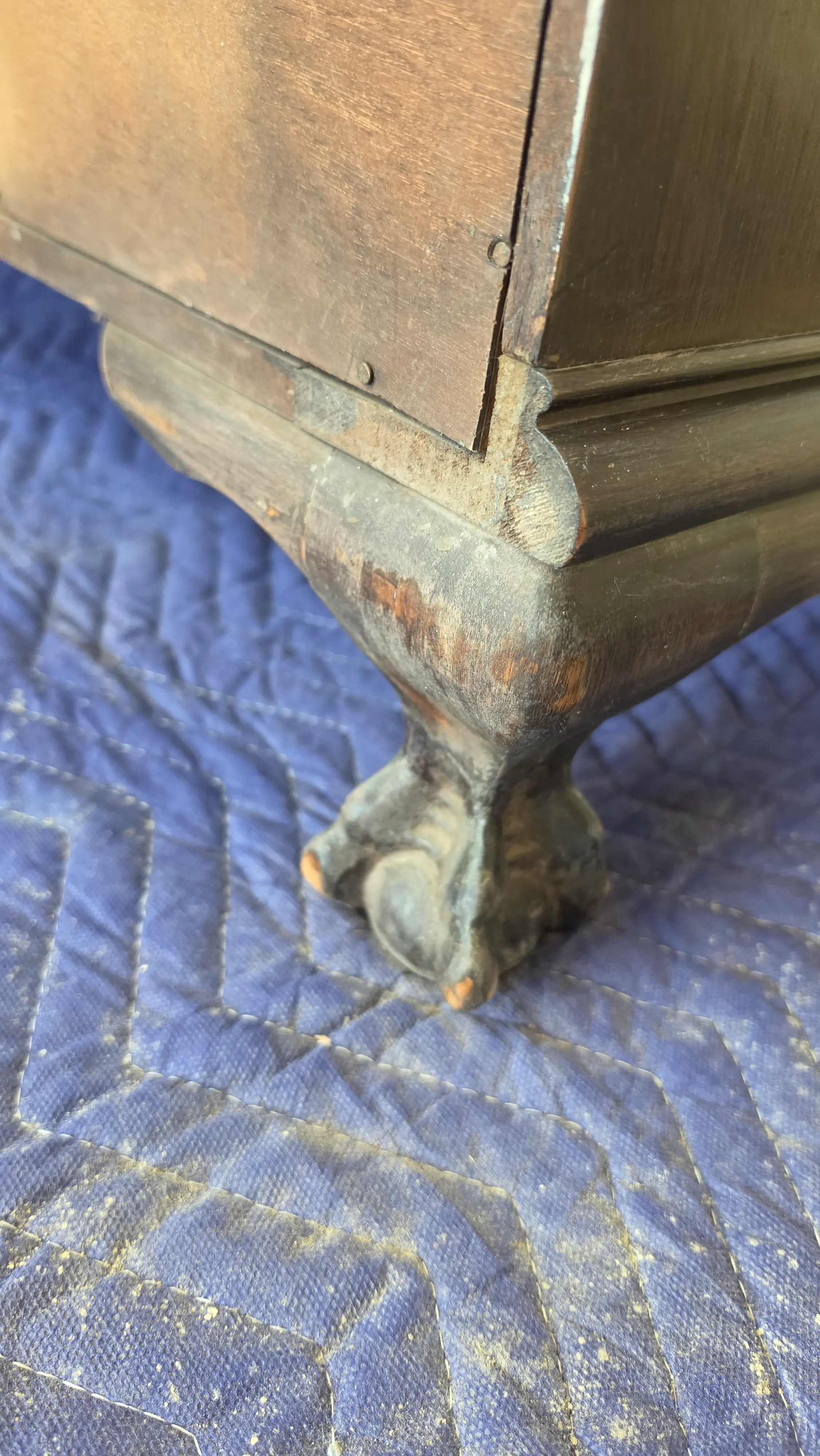 Carved ball and claw foot on an antique desk before restoration, worn through to bare wood at the toes